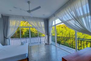 a bedroom with two beds and a balcony with windows at Zodiak in Tangalle