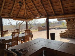 un patio con mesa, sillas y pared de piedra. en Klipdrift Sands Bush Camp, en Dinokeng Game Reserve