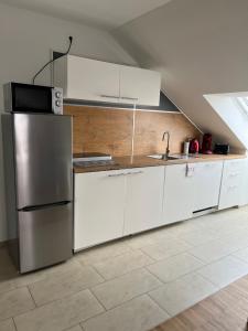 a kitchen with white cabinets and a stainless steel refrigerator at New Age Boardinghaus Bad Wimpfen in Bad Wimpfen