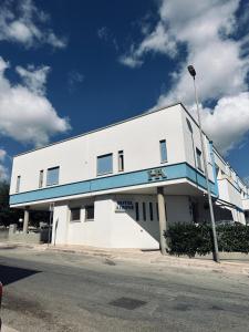 a white building with a blue stripe on it at Hotel Airone in Alberobello