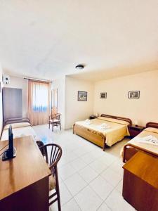 a hotel room with two beds and a desk at Hotel Airone in Alberobello