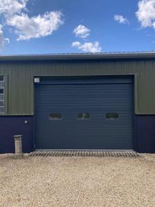 a blue garage door on a green building at Delightful Pretty Cottage in Banbury