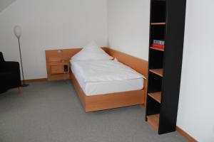 Katholisch-Soziales Institut في سيغبورغ: غرفة نوم صغيرة مع سرير ورف كتاب
