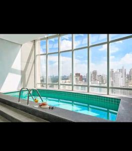 圣保罗Flat confortável próx Ibirapuera e Jardins com garagem的一座大型游泳池,位于一座带大窗户的建筑内