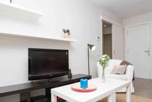 ein Wohnzimmer mit einem TV und einem weißen Sofa in der Unterkunft Port V Apart centrico con estilo 21 in Barcelona