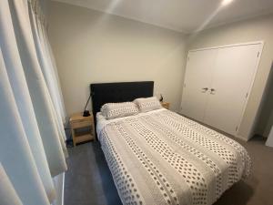 a bedroom with a bed with a white comforter at Hamilton Hospital Retreat - 2 Bedroom Townhouse Modern Warm Quiet in Hamilton