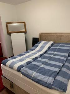 a bed with a blue and white striped blanket on it at Luxus Apartment in duisburg in Duisburg