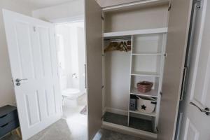 a bathroom with a closet with a toilet and a door at APPLECROFT - Escape to the Peak District National Park in Buxton