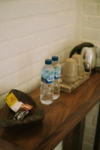 two bottles of water sitting on top of a wooden counter at The Kelong Trikora Resort in Kangkakawal