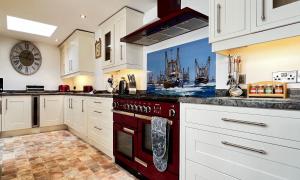 a kitchen with white cabinets and a red oven at Fisherman's Wharf in Brixham