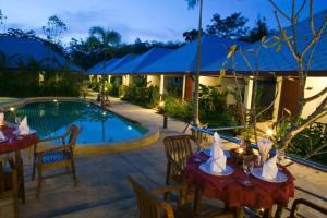 Baan Chong Fa Resort في خاو لاك: منتجع فيه مسبح وطاولات وكراسي