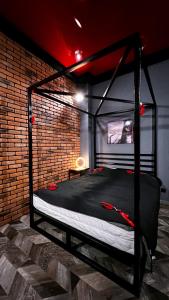 a black bed in a room with a brick wall at BDSM Red Room Apartment in Łódź