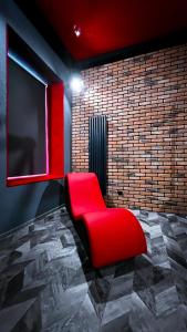 einen roten Stuhl in einem Zimmer mit Ziegelwand in der Unterkunft BDSM Red Room Apartment in Łódź