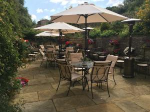 un patio con tavoli, sedie e ombrelloni di White Hart Ufford- Stamford a Ufford
