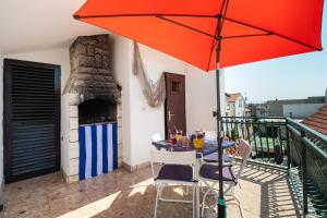 a patio with a table and an umbrella on a balcony at House Brunac with parking in Vodice