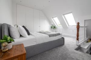 een slaapkamer met een bed met witte muren en ramen bij Spacious 3 BR house wParking & Garden, Wimbledon in New Malden