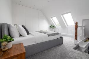 a bedroom with a bed with white walls and windows at Spacious 3 BR house wParking & Garden, Wimbledon in New Malden