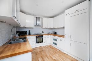 a kitchen with white cabinets and a wooden floor at Spacious 3 BR house wParking & Garden, Wimbledon in New Malden