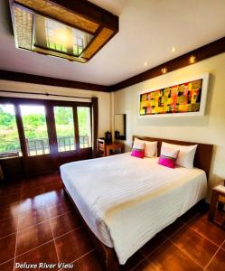 1 dormitorio con 1 cama blanca grande con almohadas rosas en Uthai River Lake Resort en Ban Nong Nam Khan