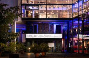 un immeuble de bureaux avec des lumières bleues sur celui-ci dans l'établissement HOTEL BERLIN KÖPENICK by Leonardo Hotels, à Berlin