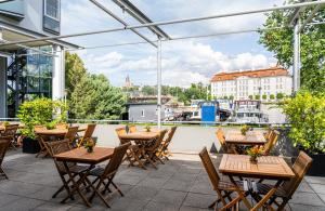 eine Terrasse mit Holztischen und -stühlen auf dem Balkon in der Unterkunft HOTEL BERLIN KÖPENICK by Leonardo Hotels in Berlin