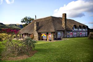 a house with a thatched roof on a green lawn at Addo Bush Palace in Addo