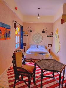 ザゴラにあるKasbah Of Peace & Boutiqueのベッドルーム1室(ベッド1台、テーブル、椅子付)