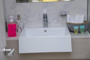 a white bathroom sink with a faucet at Tamm - Luxe Condo With Balcony and Incredible City Views in Dubai