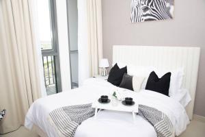 ein Schlafzimmer mit einem weißen Bett und einem Tisch darauf in der Unterkunft Tamm - Luxe Condo With Balcony and Incredible City Views in Dubai