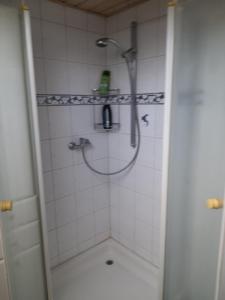 uma casa de banho com um chuveiro numa parede de azulejos brancos em Trochtelfingen F1 em Trochtelfingen
