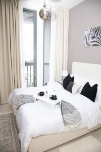 a bedroom with a white bed with a table on it at Tamm - Luxe Condo With Balcony and Incredible City Views in Dubai