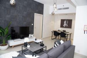 a living room with a couch and a tv at Tamm - Luxe Condo With Balcony and Incredible City Views in Dubai