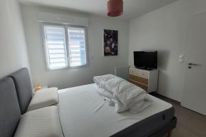 a white bedroom with a bed and a television at Maison avec jardin sur Berck in Berck-sur-Mer