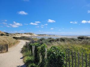 uma estrada de terra que leva a uma praia com uma cerca em Maison avec jardin sur Berck em Berck