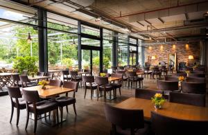 een restaurant met houten tafels, stoelen en ramen bij HOTEL BERLIN KÖPENICK by Leonardo Hotels in Berlijn