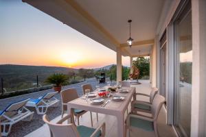 a white table and chairs on a patio with the sunset at Sunset house in Višnjevo