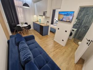 ein Wohnzimmer mit einem blauen Sofa und einer Küche in der Unterkunft DeMar Apart STAR in Lwiw