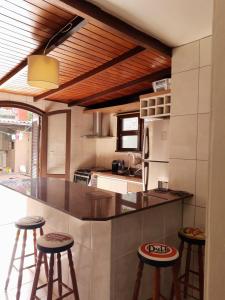 - une cuisine avec un comptoir et des tabourets dans l'établissement Apartamento com pátio e anexo exclusivo, à Torres