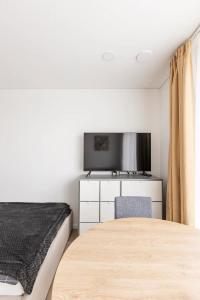 a bedroom with a bed and a flat screen tv at Ozo eco apartments in Vilnius