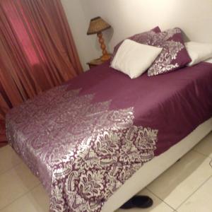 a bed with a purple comforter and pillows at C8 Surfside in Durban