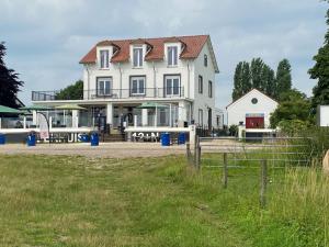 a large white house with a fence in front of it at Het Veerhuis in Oeffelt