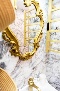 a bathroom with a gold mirror on the wall at Appartement de la noblesse - designed by C.M in Sélestat