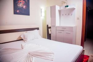 a bedroom with a white bed and a cabinet at RIVER APPARTS in Brazzaville