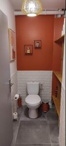 uma casa de banho com um WC branco numa parede laranja em Maison de village avec une pièce de vie lumineuse em Saint-Paul-de-Fenouillet