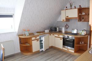 cocina pequeña con armarios blancos y fogones en Ferienwohnung Schmetterling, en Trendelburg