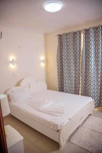- un lit blanc dans une chambre avec rideau dans l'établissement RIVER APPARTS, à Brazzaville