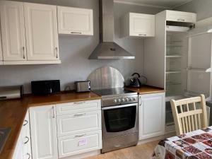 a kitchen with white cabinets and a stove top oven at 1 Bedroom Home - Private Balcony - Parking On Site in Tórshavn