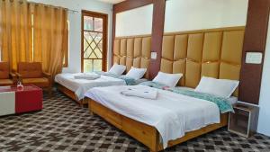 a hotel room with two beds and a chair at Hotel Gulsitara-Kunzer Gulmarg in Gulmarg