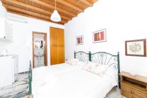 ein weißes Schlafzimmer mit einem Bett mit rosa Kissen in der Unterkunft Agerino in Moutsoúna