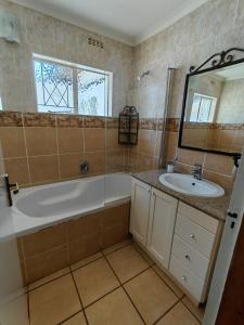 y baño con bañera, lavabo y espejo. en Emfuleni Boughton Inn, en Pietermaritzburg